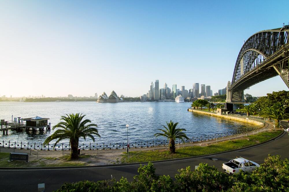 Rental Yield - View of Opera House Australia with Sydney Harbour Bridge over a road where a car is moving past