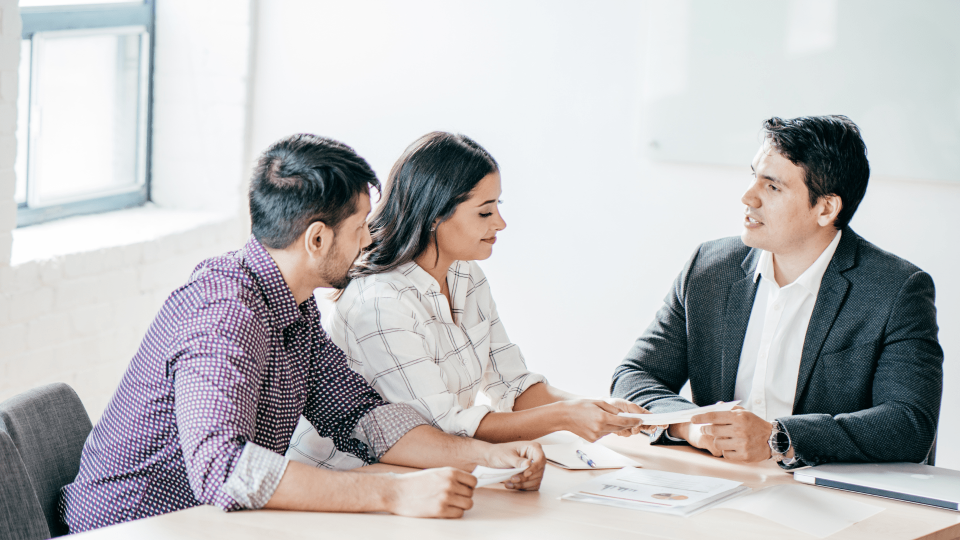 man and woman speaking to a professional in a suit and pointing at documents 