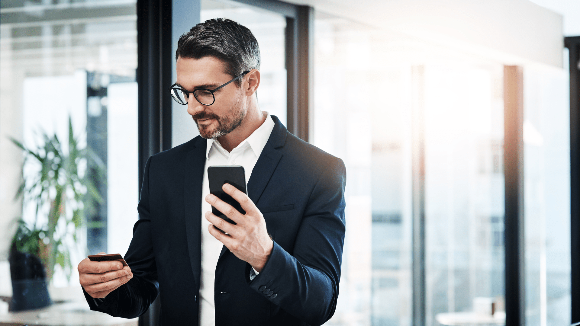 man in a suit looking at this phone and credit card