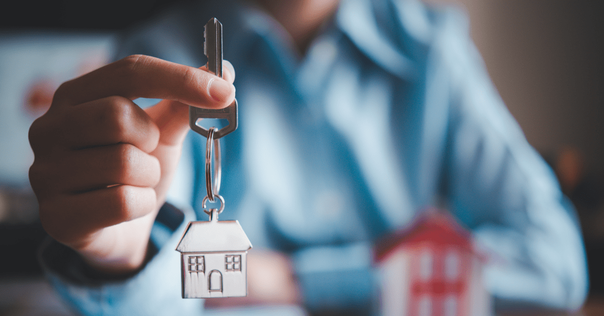 Rental Income - A person showing a key with metal keyring of a house