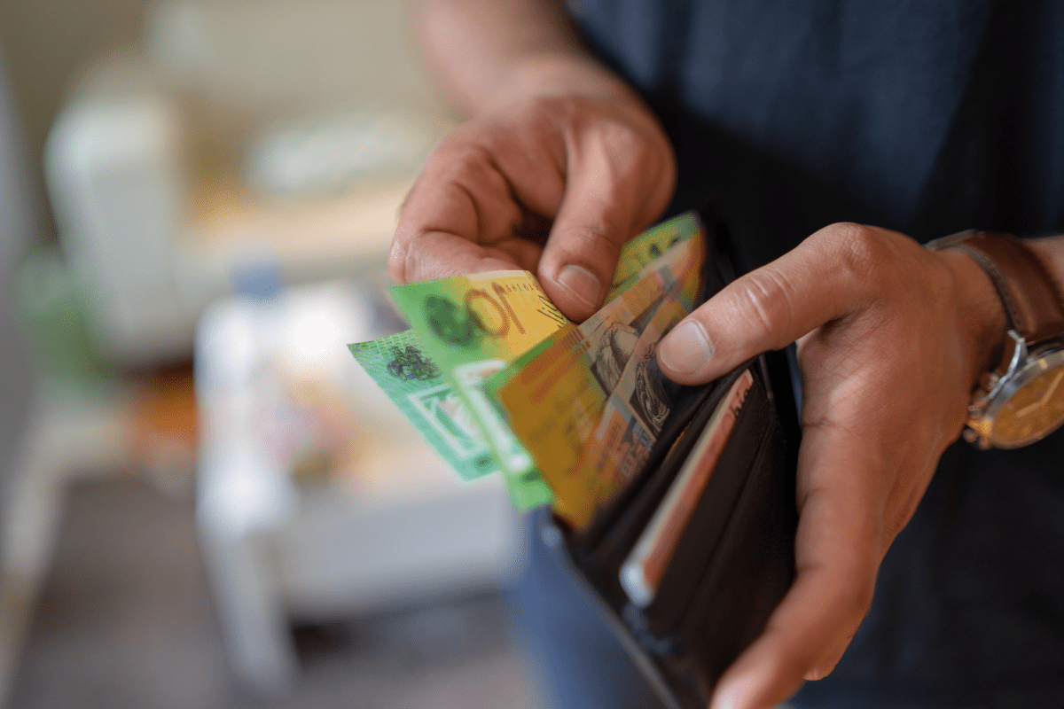 Man putting out Australian money from money bag