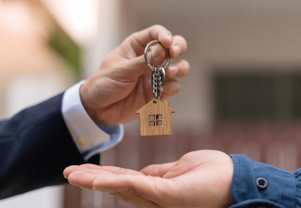 A property selling agent is handing over an property to a property buyer who made his first property investment as a first home buyer