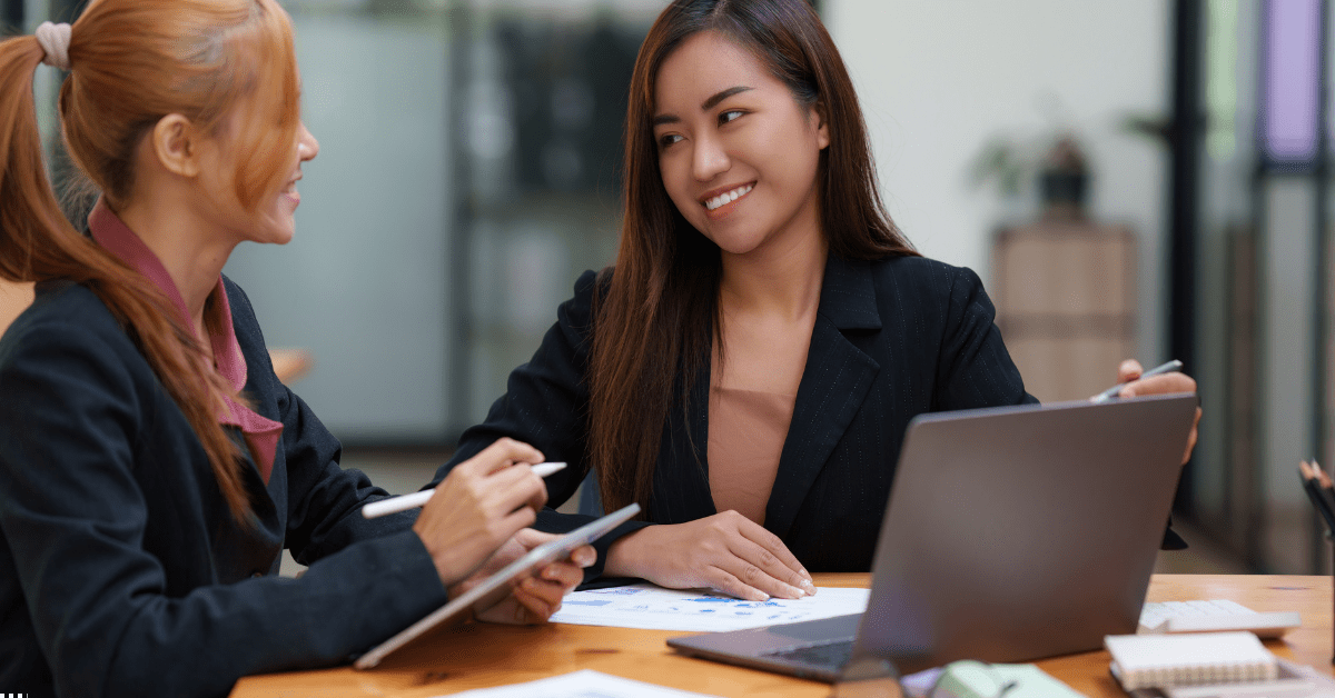 Investing in SMSF - Image of two women discussing on property investment and there is a laptop on a desk they are sitting and there's also a iPad with Magic Pen on other woman's hand. 