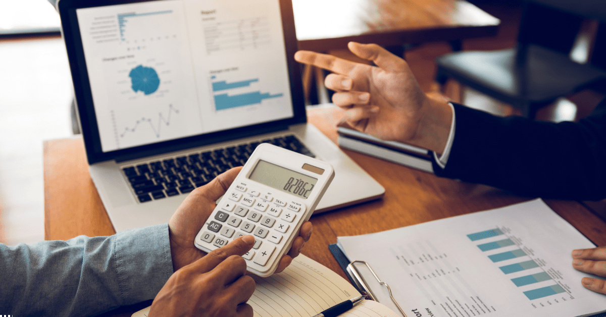SMSF Property - Two professionals discussing cost on calculator and there's a laptop showing analytics of data and also a report on those property investment analytics
