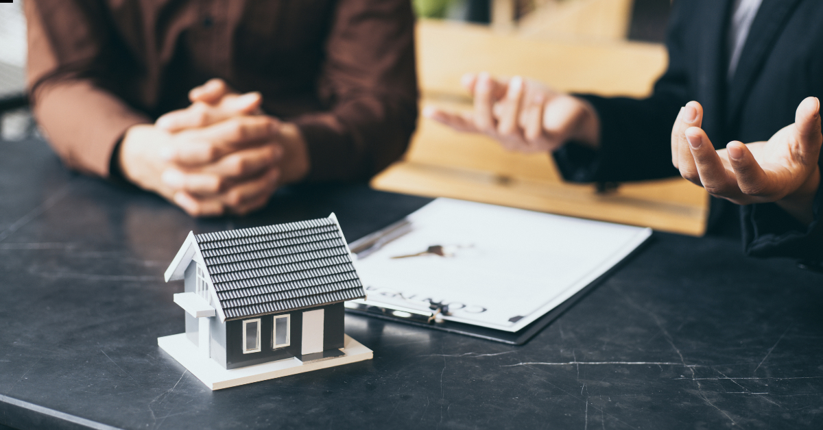 Wealth Building Through Property - Two Persons Have Discussion and There Is a Dummy Home on the table
