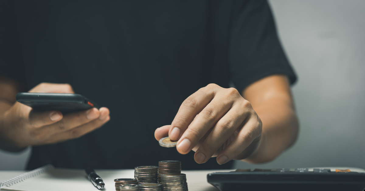 Wealth building through property - Man saving coins and holding phone seeing his financial dashboard