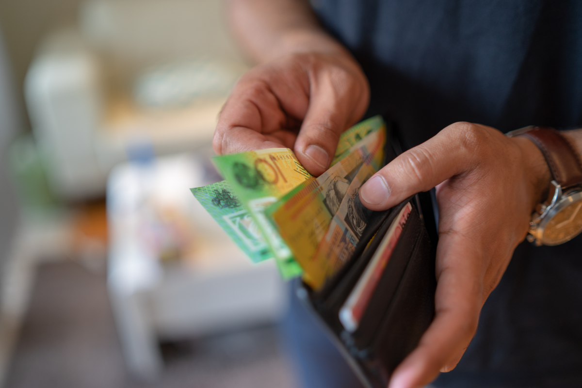 Man putting out Australian money from money bag